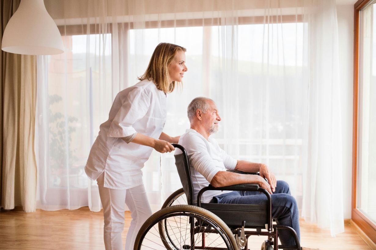 Old man on a wheelchair enjoying the view with his caregiver