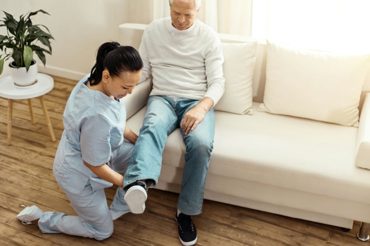 Caregiver helping disbaled man with foot exercises