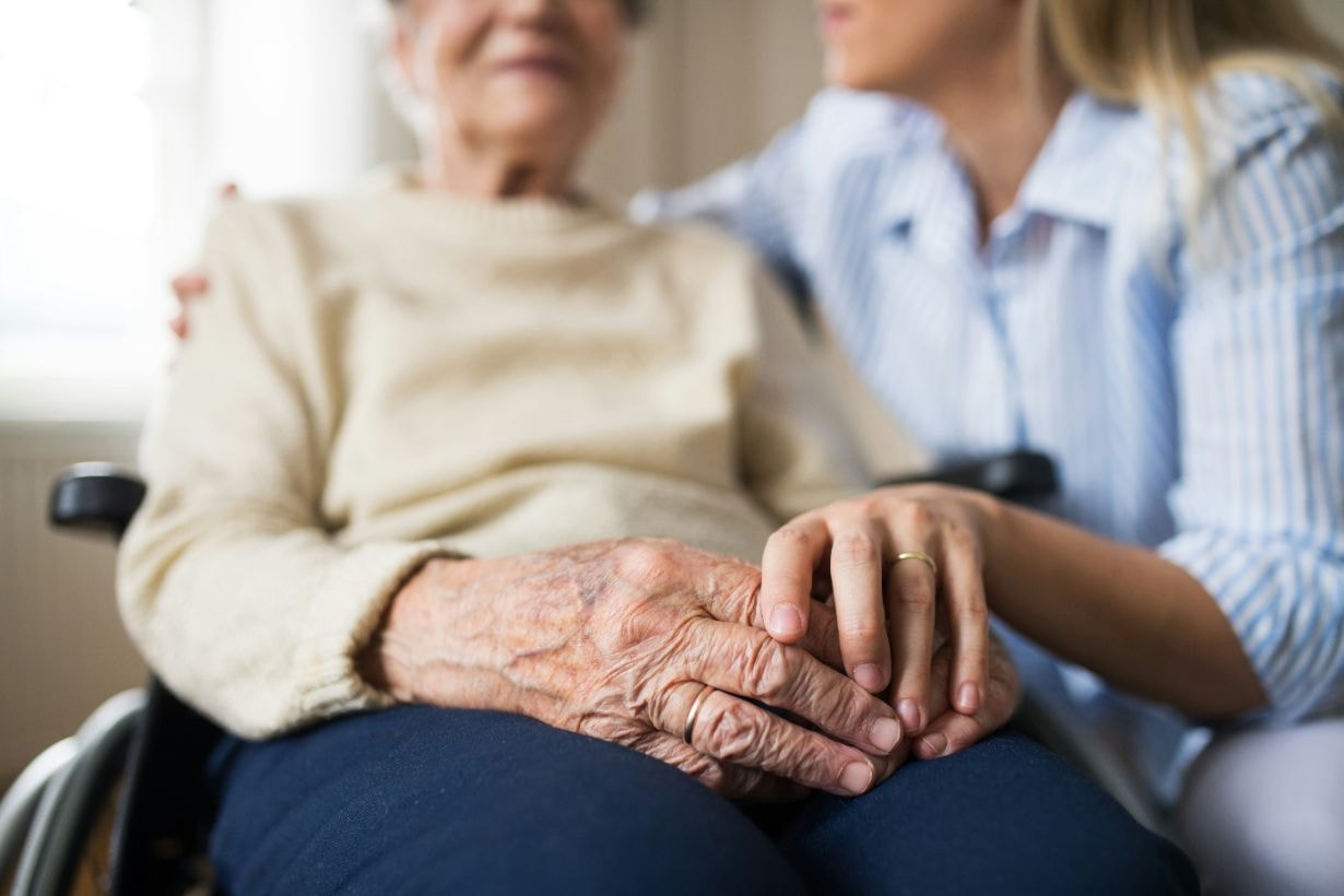 Caregiver comforting senior disabled lady