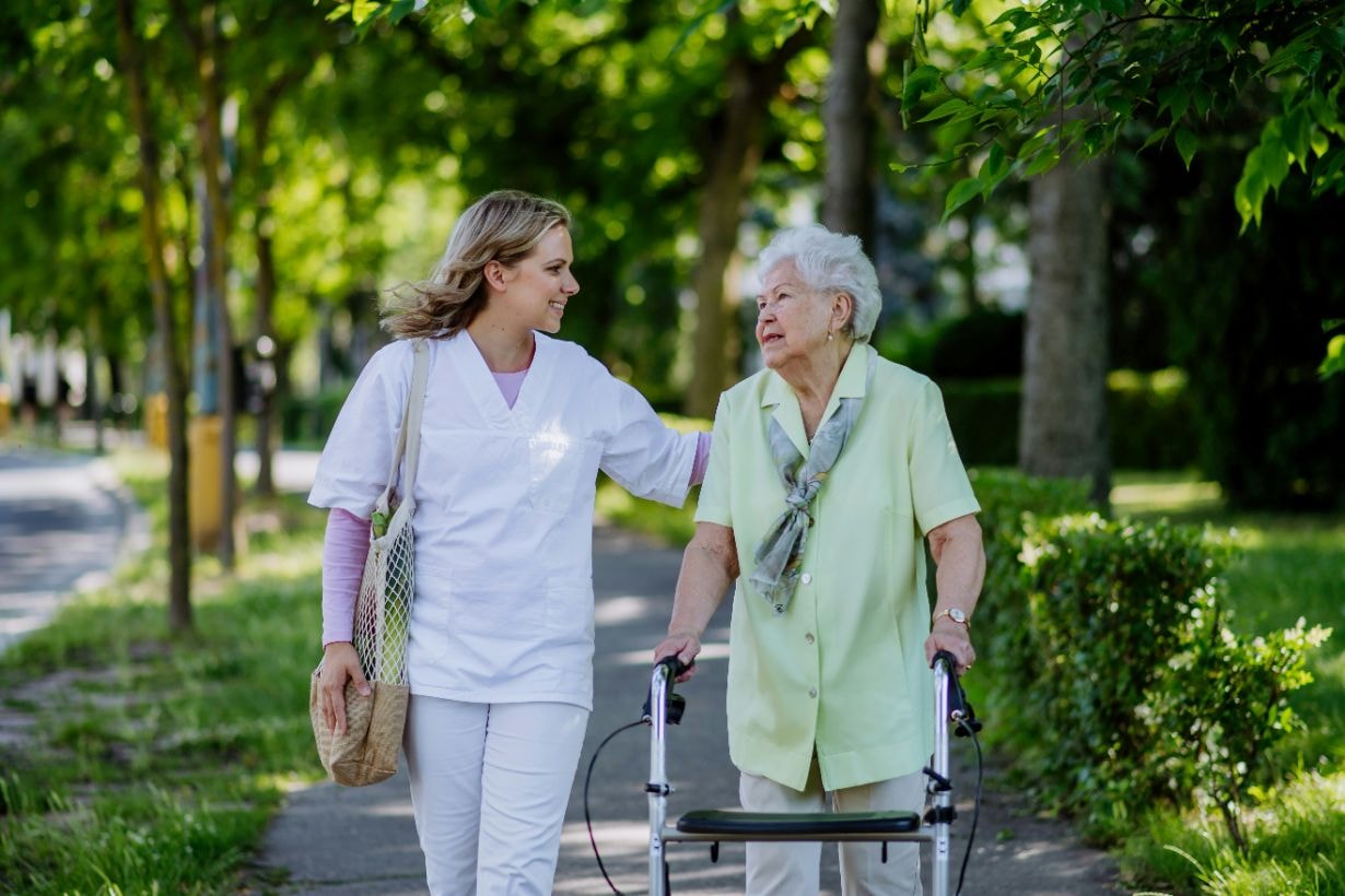 Old lady with her walker and taking a strolll with her caregiver