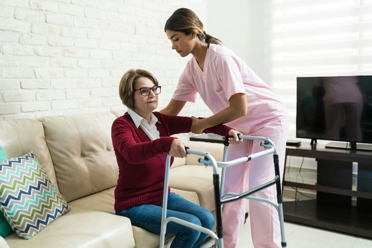 Cargiver helping old lady to walk using her walker