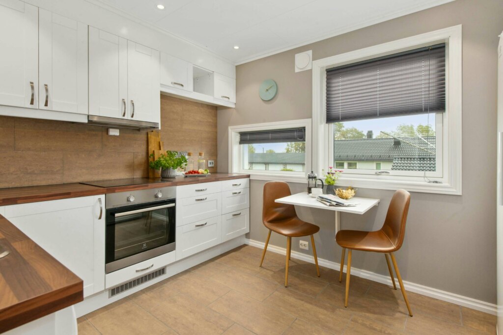 Modern kitchen interior with NDIS housing white cabinetry, wooden countertops, and a small dining area.