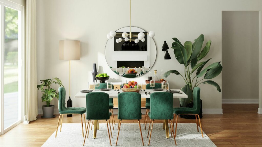 Modern dining room with a white table set for six, surrounded by green velvet chairs, large plants, and a circular mirror on the wall.