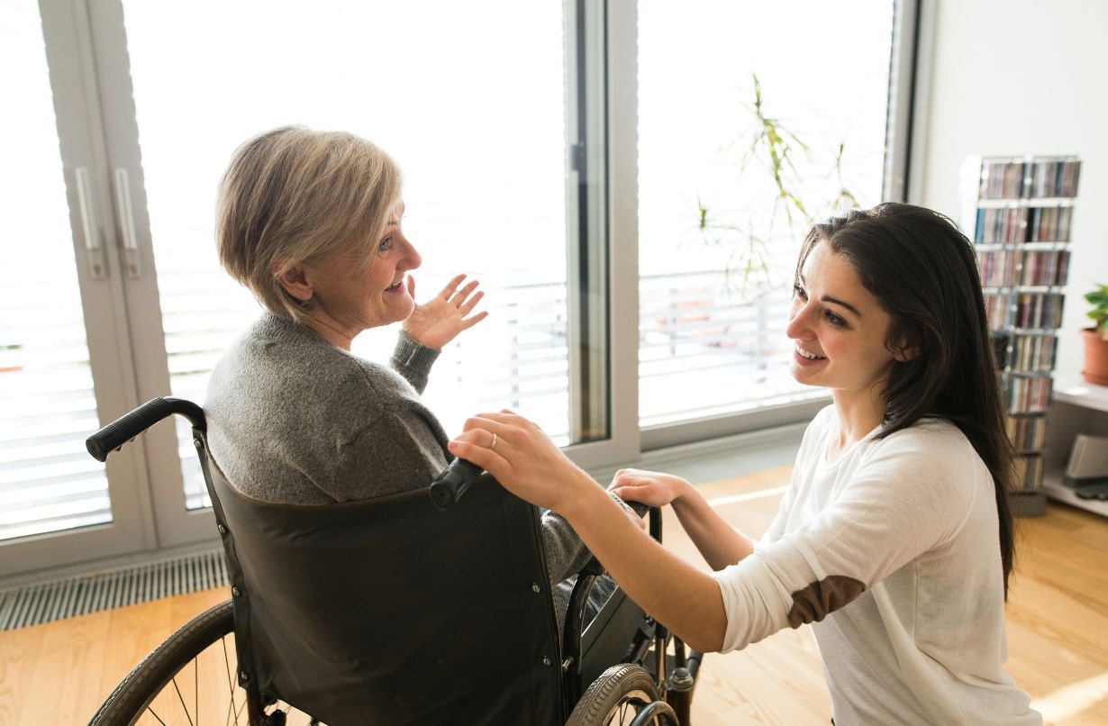 Caregiver comforting old lady in wheelchair