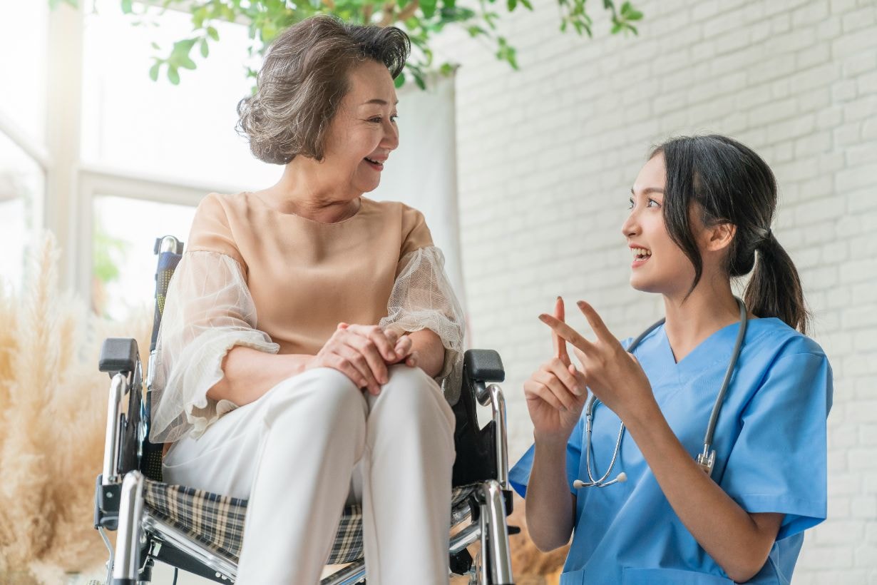 Caregiver and senior disabled lady on a wheelchair enjoying a chat