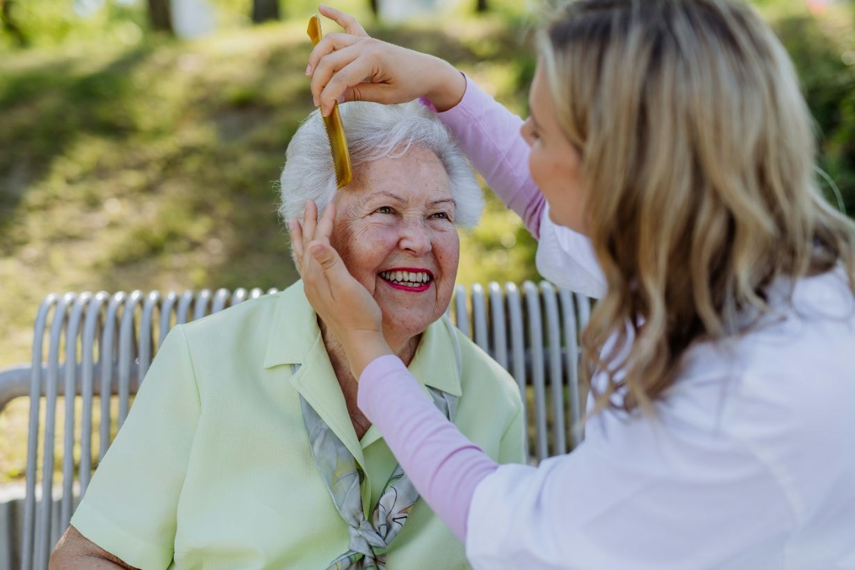 Lady caregiver combing the old lady's hair